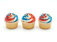 Decorated cupcakes with red, white and blue frosting swirls topped with colorful sprinkles and star candies, isolated on white background for bakery, celebration and party design projects.