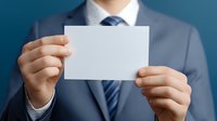 Businessman in navy suit holding blank white business card or name card against blue background, mockup for corporate branding design presentation.