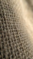 Close-up macro shot of natural burlap fabric texture with woven jute fibers in warm beige tones, shallow depth of field for textile and craft backgrounds.