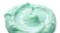 Mint green whipped cream or frosting swirl with glossy texture isolated on white background, suitable for bakery, dessert, and confectionery design projects.