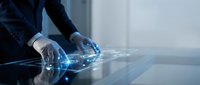 Professional businessman using futuristic holographic interface technology with glowing blue digital elements on modern glass table in corporate office.