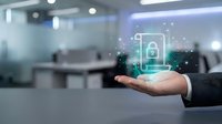 Businessman hand holding digital security lock icon with circuit board pattern in modern office environment representing cybersecurity and data protection.