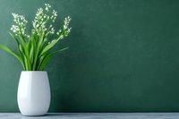 White lily of the valley flowers in modern ceramic vase against dark green wall background with copy space. Minimalist spring home decor on gray surface.