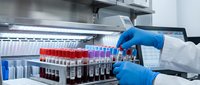 Laboratory technician in blue gloves handling blood sample tubes in medical testing facility for clinical analysis and diagnostic research.