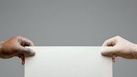 Two hands of different ethnicities holding blank white paper against neutral gray background for messaging or advertising.