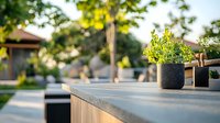 Outdoor living space with concrete countertop and potted plants at sunset, modern backyard patio design featuring minimalist furniture and natural lighting.