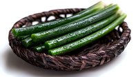 Fresh wet green okra pods arranged in woven dark brown basket, raw organic vegetables with water drops on surface, natural food photography.