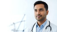 Professional South Asian male doctor with stethoscope in modern medical clinic environment for healthcare and medicine concepts.