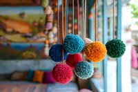 Colorful handmade yarn pompoms hanging as decorative elements in craft shop window display for DIY projects and textile arts.