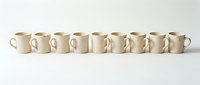 Row of nine beige ceramic coffee mugs arranged in line on white background, minimalist kitchen tableware for cafes and restaurants.