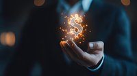 Glowing dollar sign floating above businessman's hand with magical sparkle effect against dark background, representing financial success and wealth management.