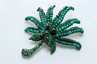 Elegant vintage emerald green beaded brooch with floral design and dark red gemstones on white background, isolated for jewelry catalogs.
