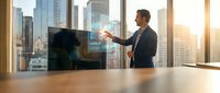 Professional businessman presenting holographic data visualization in modern office conference room with city skyline view during golden hour sunset.