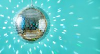 Shiny disco ball reflecting light beams against turquoise background creating sparkly party atmosphere for nightclub events and celebrations.