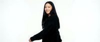 Young Asian woman in black sweater sitting and smiling on white background, isolated portrait for lifestyle and fashion design projects.
