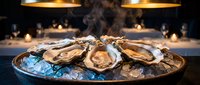 Fresh oysters served on ice platter in elegant restaurant setting with warm ambient lighting for gourmet seafood dining experience.