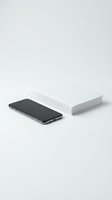Modern smartphone with blank screen next to white book on neutral background for mockup and branding projects.