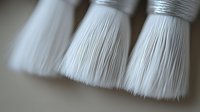Close-up of white shaving brushes with silver ferrules showing fine bristle texture and detail. Useful for grooming, barbershop, or men's care product marketing.
