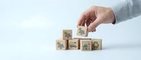 Hand placing wooden cube with green energy icon completing sustainable development goals concept on white background for environmental presentations.