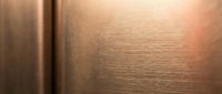 Brushed copper metal surface with warm lighting and subtle texture variations, suitable for backgrounds, design elements, and industrial applications.