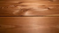 Natural wood grain texture background with warm brown tones and visible knots. Hardwood flooring surface for interior design and construction projects.