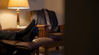 Cozy leather armchair with warm lamp lighting creating comfortable reading corner atmosphere for relaxation and home interior design concepts.