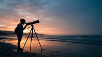 Silhouetted child looking through telescope on beach at sunset, observing sky and stars for astronomy education and exploration.