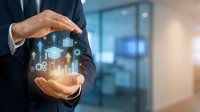 Businessman in dark suit holding glowing digital hologram displaying financial charts, graphs, and data analytics icons in cupped hands against modern office background.