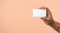 Close-up of hand holding blank white business card against neutral beige background. Isolated on solid color for branding, marketing, and corporate design mockups.