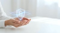Professional woman hands presenting glowing digital security shield icon with protective wings symbolizing cybersecurity and data protection services.
