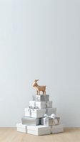 Wooden goat figurine standing atop stacked gift boxes with silver and white ribbons on wooden floor against neutral background. Suitable for holiday marketing, retail displays, and seasonal promotions.