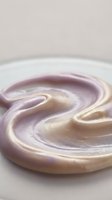 Swirled cream and lavender liquid creating smooth, flowing patterns in a shallow white bowl for cosmetic and culinary applications.