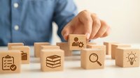 Business professional selecting wooden cube with team icon from collection of corporate symbols representing human resources management and organizational development.