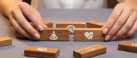 Hands protecting wooden blocks with insurance icons representing life, health and property coverage for financial security and risk management planning.
