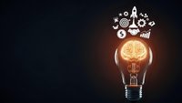 Light bulb with glowing brain inside surrounded by business innovation icons on dark background representing creative thinking and entrepreneurship.