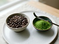 Coffee beans and matcha green tea powder in ceramic bowls on white plate, healthy beverage ingredients for morning drinks and wellness lifestyle.