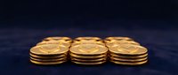 Stack of golden coins arranged in three groups on dark surface, representing wealth, savings, investment, and financial success.