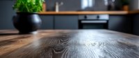 Close up view of wooden table surface showing natural grain texture and pattern in modern kitchen interior with decorative plant in background. Selective focus.