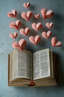 Pink paper hearts floating above open book on blue background for romantic literature, love stories, Valentine's Day cards and wedding invitations.