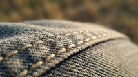 Close-up macro shot of woven fabric texture showing detailed thread patterns and textile fibers in neutral tones for interior design and crafting projects.