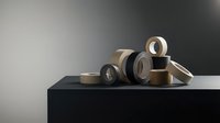 Various adhesive tape rolls in neutral colors arranged on modern surface for packaging and office supplies applications.