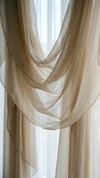 Sheer beige curtains with elegant draped swags frame a bright window, creating soft natural light and sophisticated interior design for home decor projects.