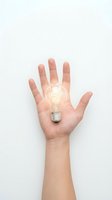 Open hand holding glowing light bulb against white background representing innovation, creativity, bright ideas and inspiration for business solutions.