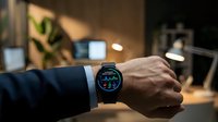 Professional businessman checking smartwatch with colorful display in modern office workspace during evening hours.