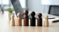 Diverse wooden figurines representing multicultural team unity and inclusion in modern office workspace for business diversity concepts.