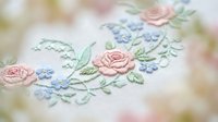 Delicate floral embroidery with pink roses and blue flowers on soft fabric, showcasing traditional needlework craftsmanship for textile and craft projects.