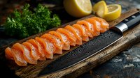 Fresh raw salmon sashimi slices arranged in row on wooden cutting board with damascus steel knife, lemon and herbs for Japanese cuisine preparation.
