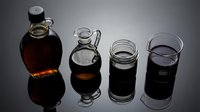 Dark syrup and molasses in glass containers on reflective surface for culinary cooking and baking ingredients.