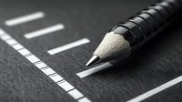 Sharp graphite pencil tip on dark textured surface with white measurement marks, macro photography showing detail and precision in monochromatic style.