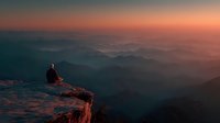 Person sitting on mountain cliff edge during golden hour sunset with layered hills stretching to horizon creating peaceful meditation moment.
